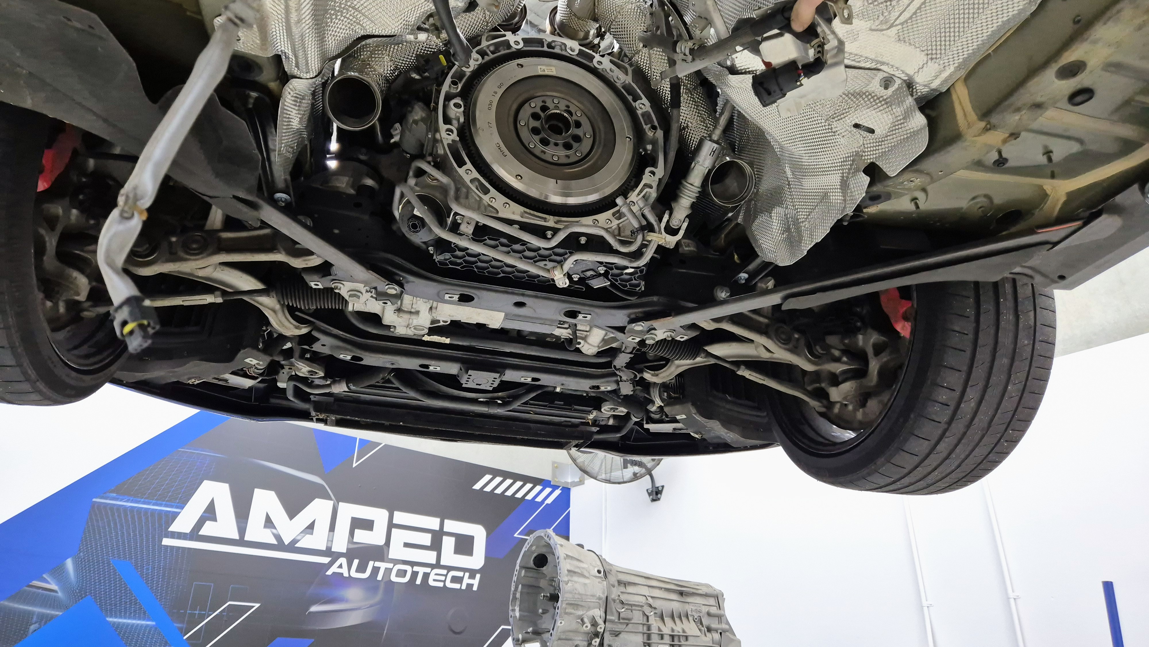 Underside of a Mercedes-AMG C63 with its gearbox removed at Amped AutoTech
